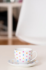 Empty coffee cup with colorful dots on white table with blurry background. Selective focus.