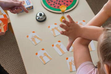 A cute little girl is engaged in a private reception with a speech therapist-woman in a playful way...