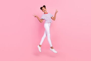 Full size photo of brown bun haired stylish african american girl wear casual clothes jump walk make v-sign isolated on pink color background