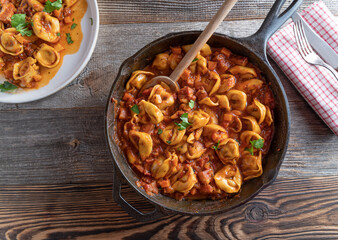 Tortellini dish with pancetta, tomtaoes and vegetable in a cast iron pan