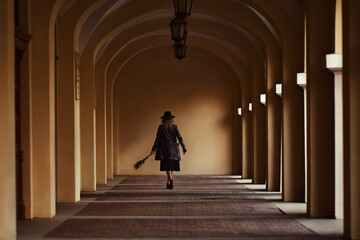 A girl in a black hat and black cloak runs turns away