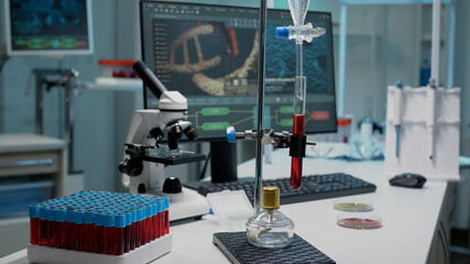 Desk with chemical equipment for experiment with test tube in laboratory. Sample of blood in flask and dripping pipe used for science with micropipette, vacutainers and microscope