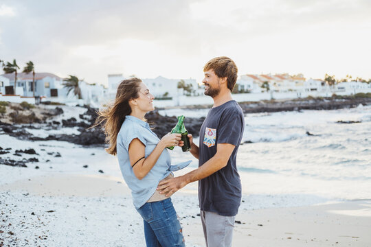 Mid Adult Couple Toasting Drinks While Standing At Beach