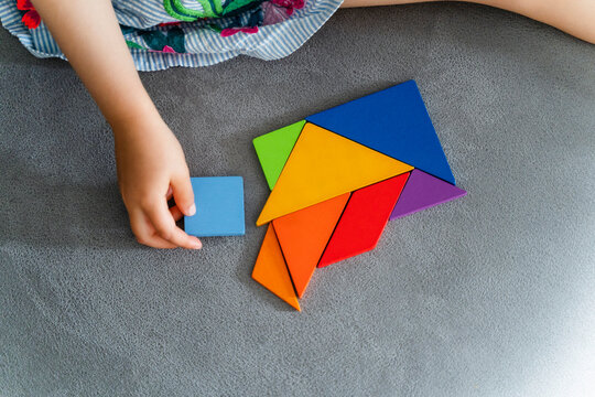 Woman playing with multi colored tangram on sofa