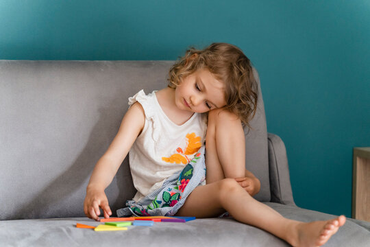 Cute girl playing with toy while sitting on sofa at home