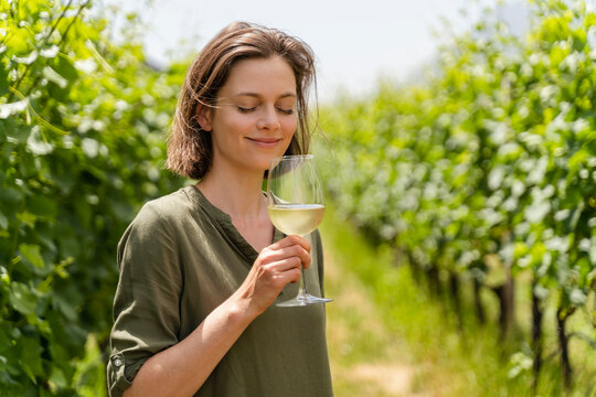 Smiling woman smelling wine while standing at vineyard - Powered by Adobe