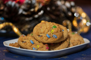 Sweet biscuits, cookies with colorful candies on a white plate, colorful lighted, blurred background