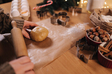 Woman using rolling pin for making gingerbread. Close-up of rolling raw dough for gingerbread. Christmas mood. Preparing for hollidays