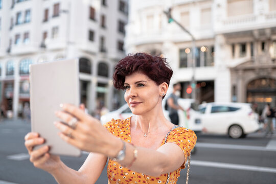 Mature woman taking selfie through digital tablet in city