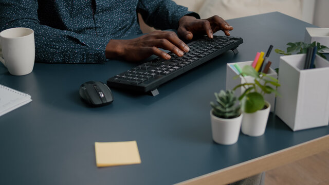 Top view of black man african american hands typing on computer keybord on a blue desk. Remote worker using PC, working from home, browsing searching online web internet communication
