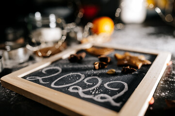 Baking Christmas gingerbread cookies on a dark wooden table. Preparing for baking. Winter holidays. 2022 New Year sign. Top view. 