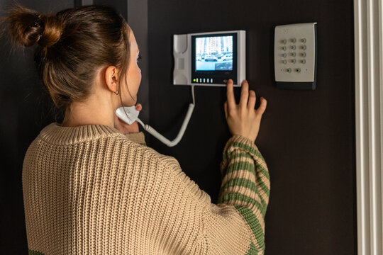 Woman Using Intercom Device At Home