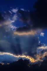 Fototapeta na wymiar Bright rays of the sun shine through dramatic clouds.