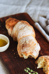 Artisan sourdough bread served with olive oil and thyme on wooden cutting board. Selective focus