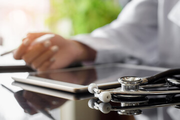 Female doctor using electronic pen work on digital tablet with stethoscope on the desk at office in clinic or hospital.