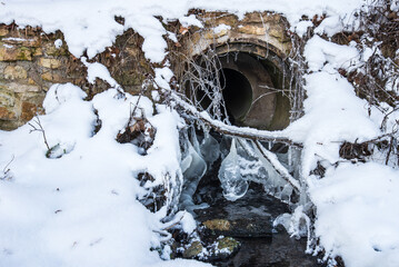 On winter day, icicles form at the culvert - obrazy, fototapety, plakaty