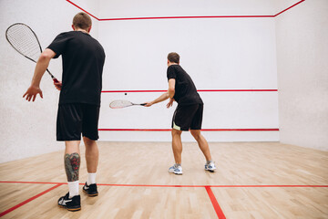 Full-length portrait of two young sportive men training, playing squash game in special sport...