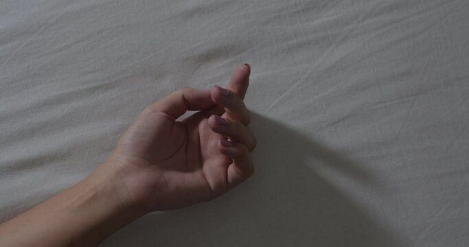 A close-up of the hands of an unrecognizable man and woman making love on a white sheet. Romance and humiliation concept