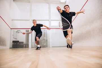 Full-length portrait of two young playful boys training together, playing squash isolated over...