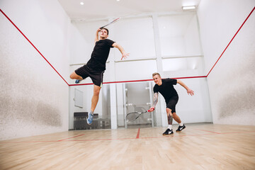 Full-length portrait of two young sportive boys training together, playing squash isolated over...