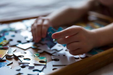 Children's hands collect puzzles. An educational game for a kid. Close-up.