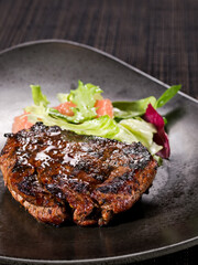 roasted filet mignon served with salad mic on a plate dark background