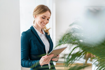 Smiling female professional looking at digital tablet in office