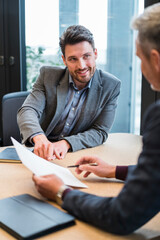 Mid adult male professional working with colleague over documents at work place