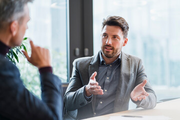 Mid adult businessman talking to mature male colleague at office