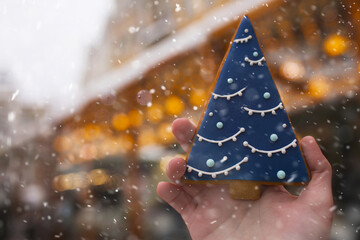 Woman's hand holding tasty ginger cookie at the New year fair