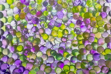 Background of green and purple water gel balls, copy space