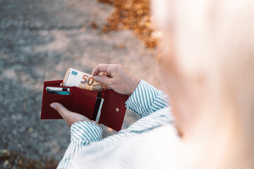 Close up of business woman hands holding a red leather wallet with 50 euro banknotes