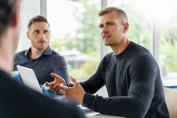 Young businessman discussing with male colleagues at office