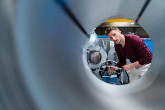 Male professional with digital tablet checking steel sheet at factory
