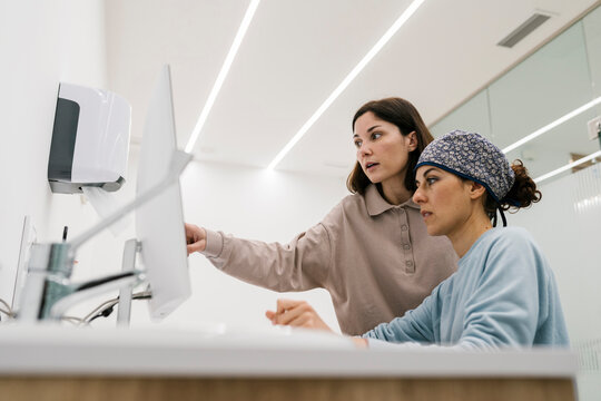 Dentist using computer while working with colleague at office