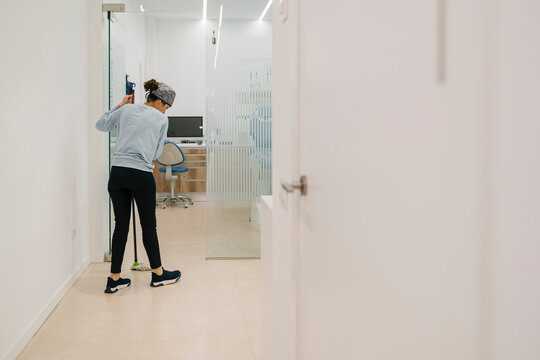 Woman Cleaning Corridor Floor In Dental Clinic