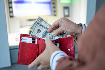 Unrecognizable female hand withdrawing money from credit card at ATM. Modern technology, banking...