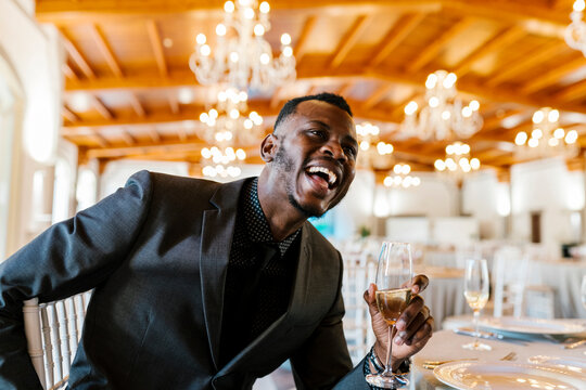 Handsome man holding champagne flute while sitting by table at banquet