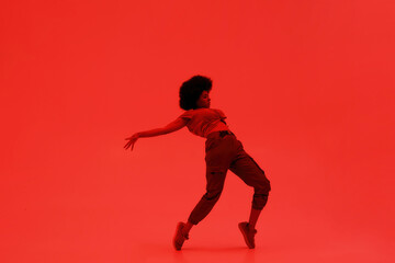 Fototapeta na wymiar Black woman dancing hip hop on red background