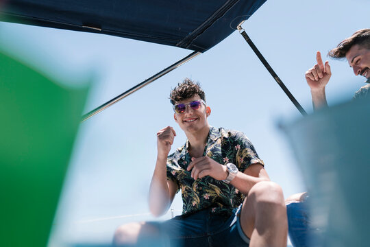 Smiling handsome young man with friend in yacht during vacation