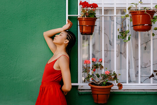 Woman with eyes closed standing by window outside house