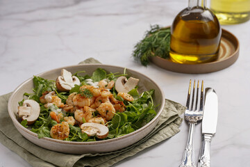 Arugula salad with shrimp and champignons, olive oil and dill on a wooden board on a white surface
