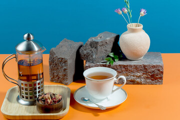 Tea in a cup in a composition with pastries and dessert, on a bright colored background.