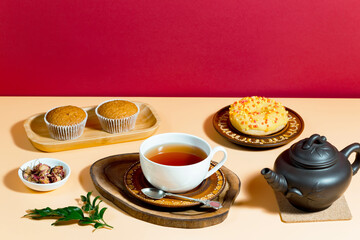 Tea in a cup in a composition with pastries and dessert, on a bright colored background.