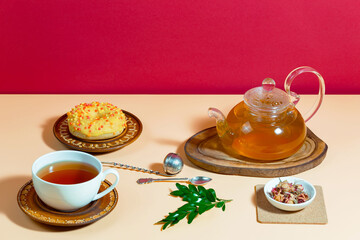 Tea in a cup in a composition with pastries and dessert, on a bright colored background.