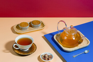 Tea in a cup in a composition with pastries and dessert, on a bright colored background.