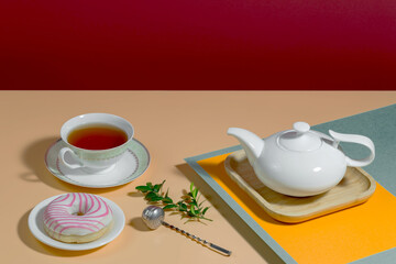 Tea in a cup in a composition with pastries and dessert, on a bright colored background.