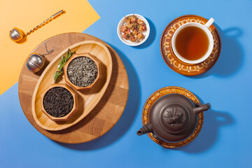 Tea in a cup in a composition with pastries and dessert, on a bright colored background.