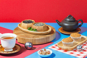 Tea in a cup in a composition with pastries and dessert, on a bright colored background.