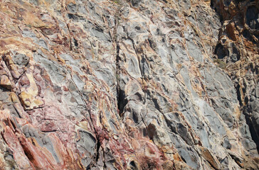 red, orange, white, yellow and black cliff rock texture on the island of milos